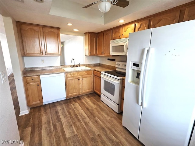 kitchen featuring dark wood-style floors, white appliances, a sink, and brown cabinets