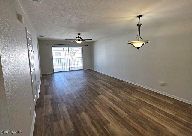 empty room with a textured ceiling, a textured wall, a ceiling fan, baseboards, and dark wood-style floors