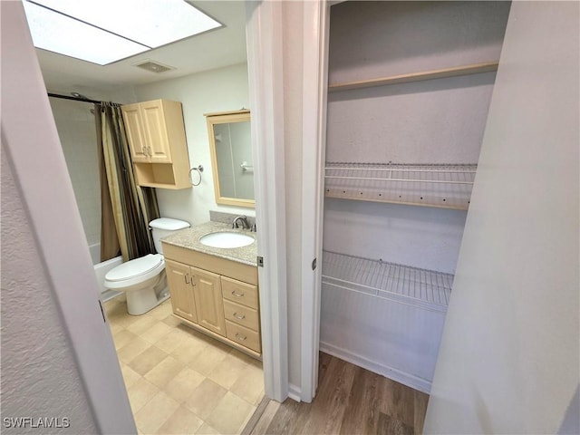 bathroom featuring toilet, a skylight, vanity, visible vents, and shower / bath combination with curtain