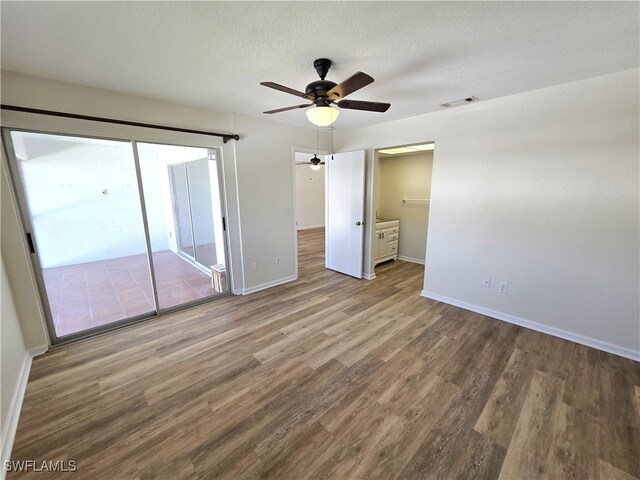 unfurnished bedroom with access to outside, a textured ceiling, baseboards, and wood finished floors