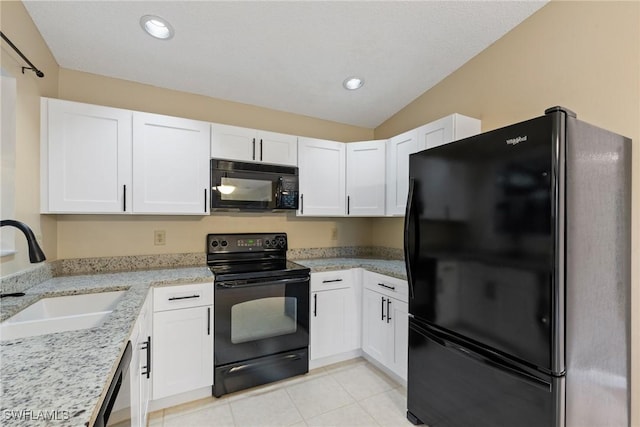 kitchen featuring light stone counters, light tile patterned flooring, a sink, black appliances, and white cabinets