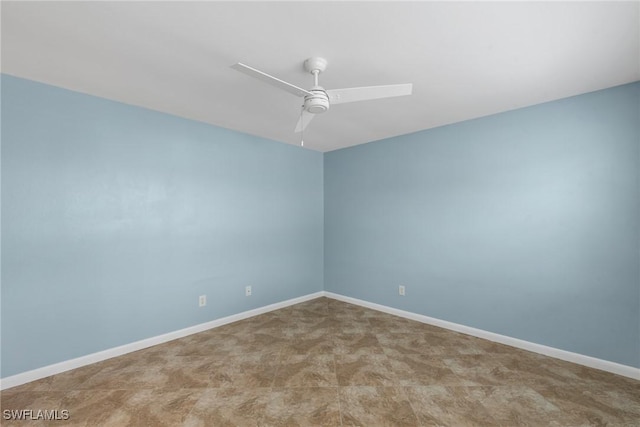 empty room with a ceiling fan and baseboards