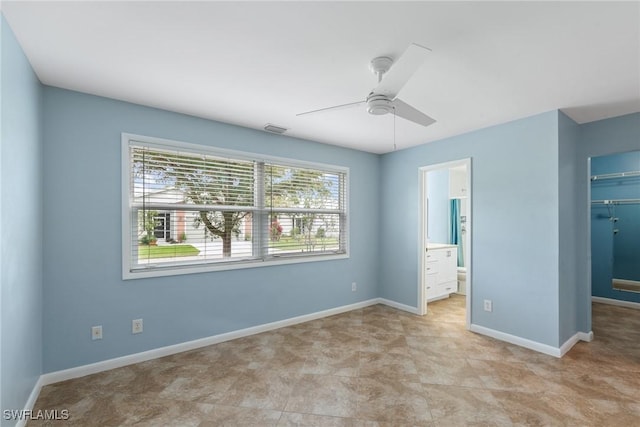 unfurnished bedroom featuring baseboards, visible vents, ceiling fan, stainless steel refrigerator, and a walk in closet