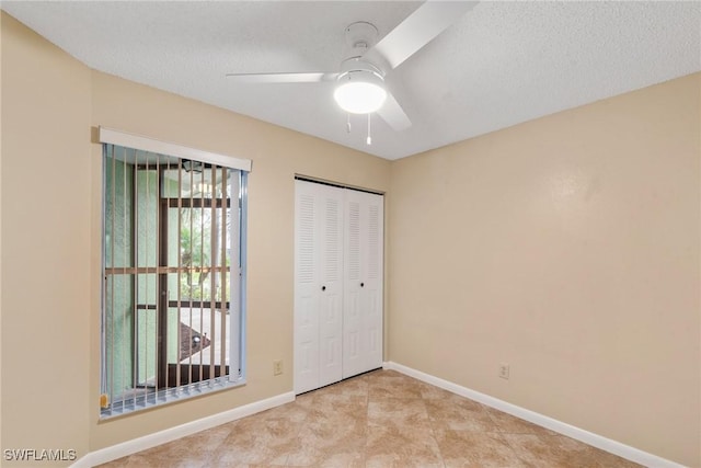 unfurnished bedroom featuring a closet, baseboards, a textured ceiling, and a ceiling fan