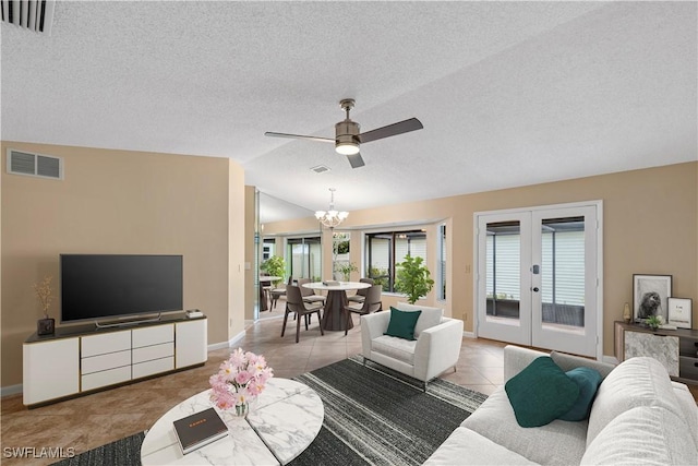 living area featuring visible vents, ceiling fan with notable chandelier, french doors, tile patterned flooring, and lofted ceiling