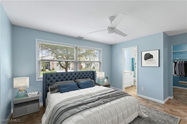 bedroom featuring visible vents, a walk in closet, ensuite bathroom, a closet, and baseboards