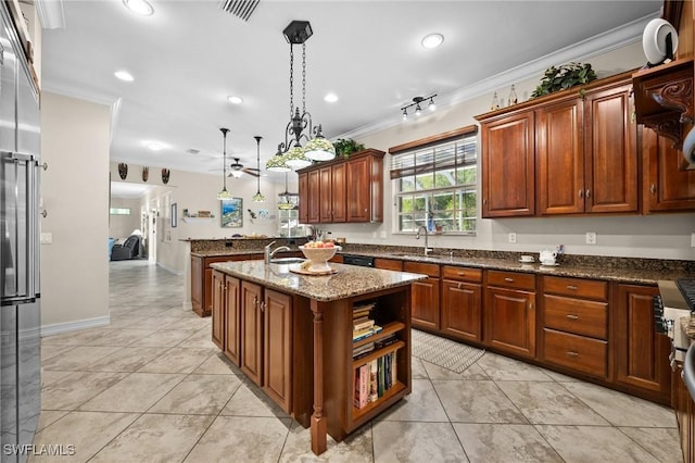 kitchen featuring dark stone countertops, a kitchen island, decorative light fixtures, and crown molding