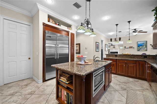 kitchen with a center island with sink, open shelves, a sink, and built in appliances