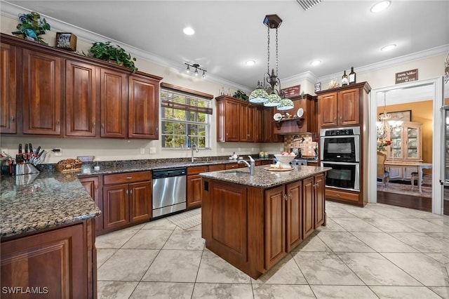 kitchen featuring ornamental molding, dark stone countertops, decorative light fixtures, a kitchen island with sink, and stainless steel appliances