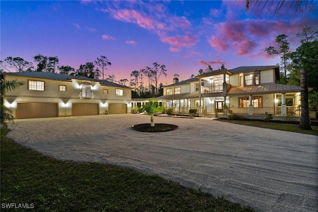 view of front of property with a garage, driveway, metal roof, a standing seam roof, and a porch