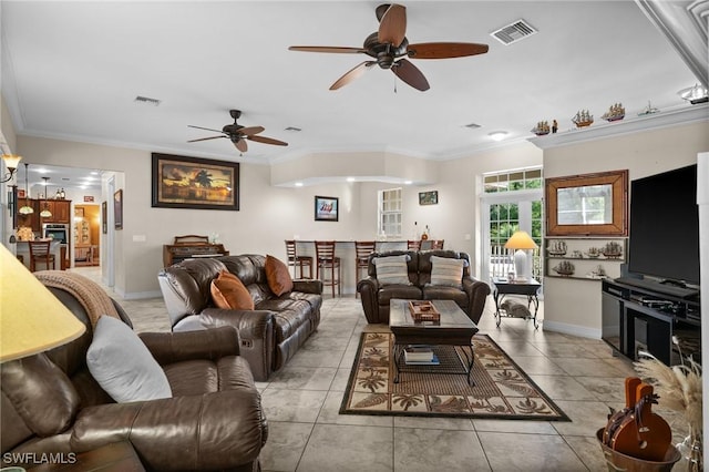 living room with baseboards, light tile patterned flooring, visible vents, and crown molding