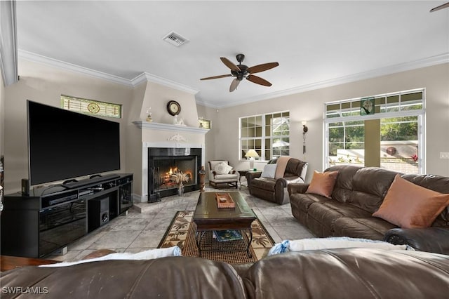 living room featuring a warm lit fireplace, ceiling fan, visible vents, and ornamental molding