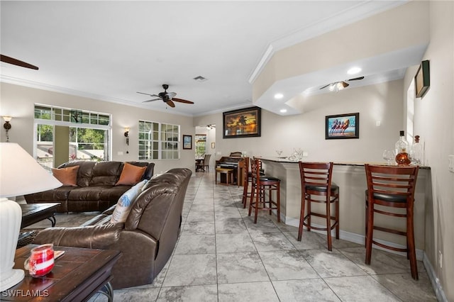 living area with ornamental molding, a bar, visible vents, and a ceiling fan