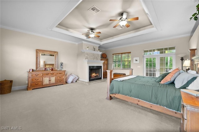 bedroom with a tray ceiling, french doors, visible vents, access to outside, and a lit fireplace