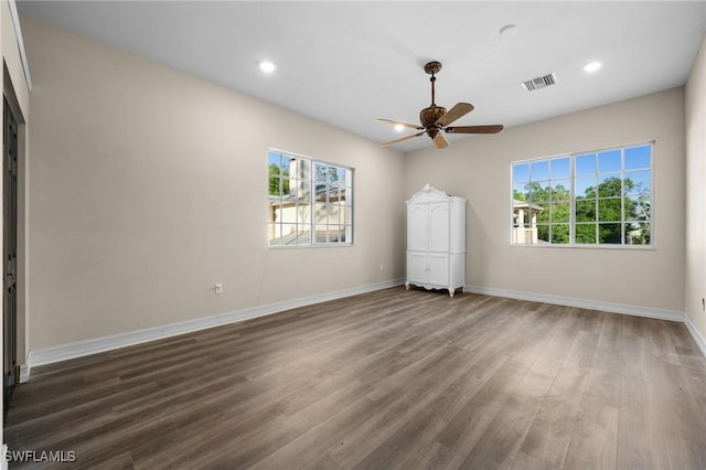 unfurnished bedroom with dark wood-style flooring, multiple windows, visible vents, and baseboards