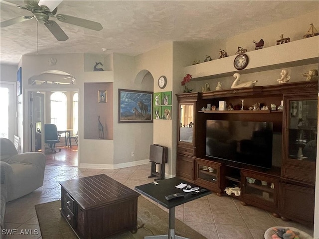 living room featuring a ceiling fan, light tile patterned flooring, a textured ceiling, and baseboards