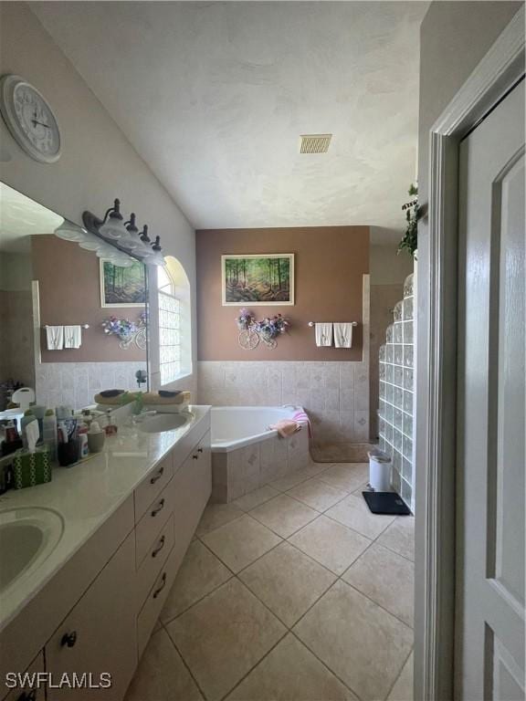 bathroom with double vanity, visible vents, tile patterned floors, a sink, and a bath