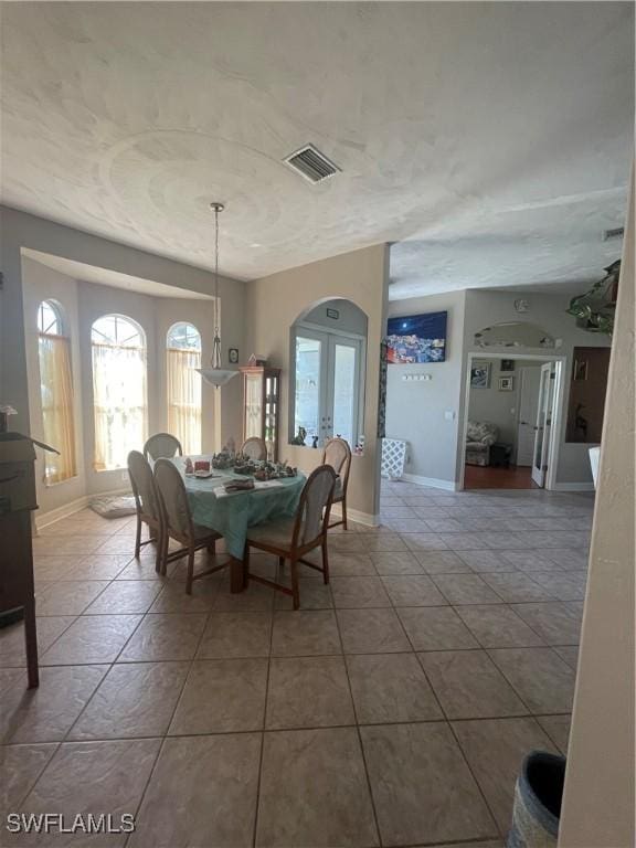 tiled dining space featuring baseboards, visible vents, and french doors