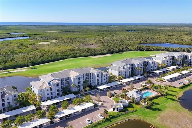 drone / aerial view with golf course view, a forest view, and a water view