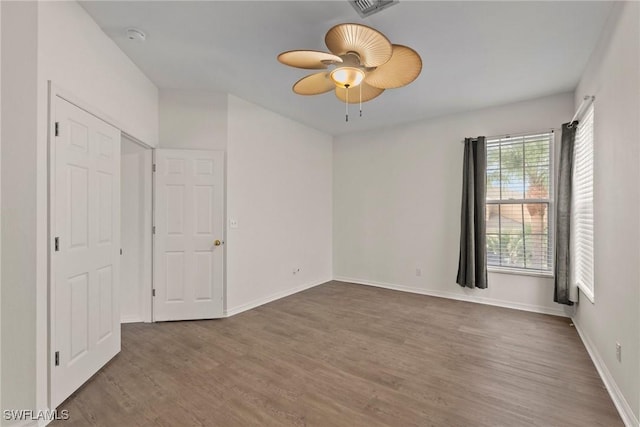 unfurnished bedroom featuring visible vents, dark wood-type flooring, a ceiling fan, and baseboards