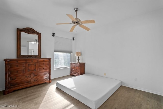 bedroom with light wood-style floors, ceiling fan, and baseboards