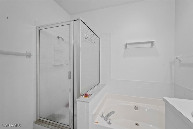 bathroom with a stall shower, a garden tub, and vanity