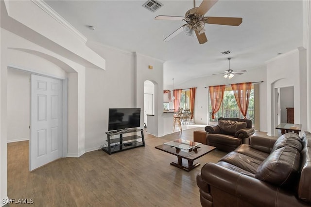 living area with baseboards, crown molding, visible vents, and wood finished floors