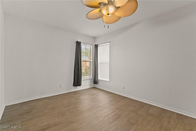 unfurnished room featuring dark wood finished floors, a ceiling fan, and baseboards
