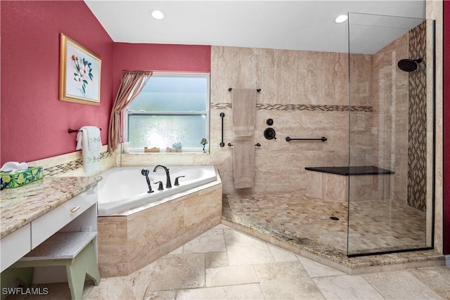 bathroom with recessed lighting, stone tile flooring, a garden tub, and a walk in shower