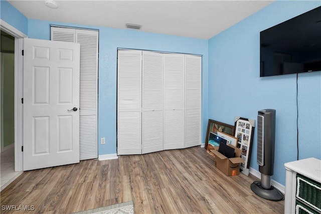 bedroom with wood finished floors, visible vents, and baseboards