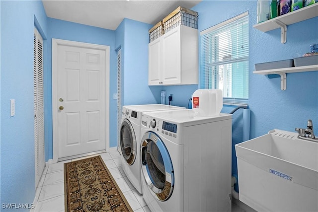 laundry area with cabinet space, light tile patterned flooring, a sink, washer and dryer, and baseboards