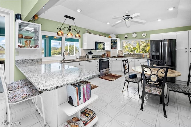 kitchen with hanging light fixtures, white cabinetry, stainless steel range oven, black microwave, and a peninsula