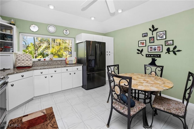 kitchen with glass insert cabinets, white cabinets, black fridge with ice dispenser, and dark stone countertops