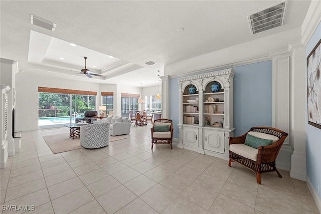 living area featuring light tile patterned floors, visible vents, and a tray ceiling