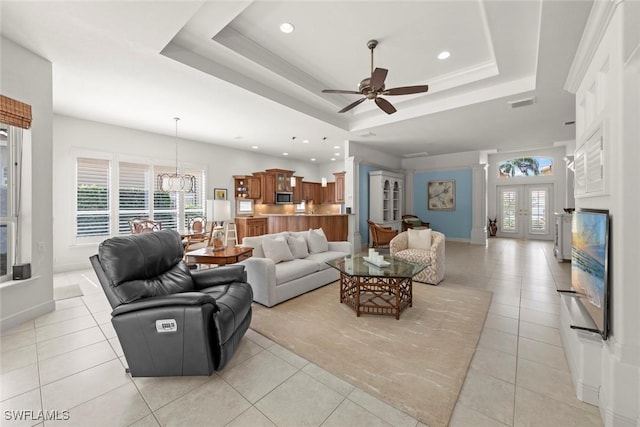 living area with light tile patterned floors, a tray ceiling, ceiling fan with notable chandelier, and recessed lighting