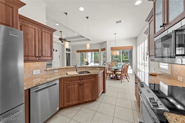 kitchen featuring a tray ceiling, stainless steel appliances, visible vents, hanging light fixtures, and a sink