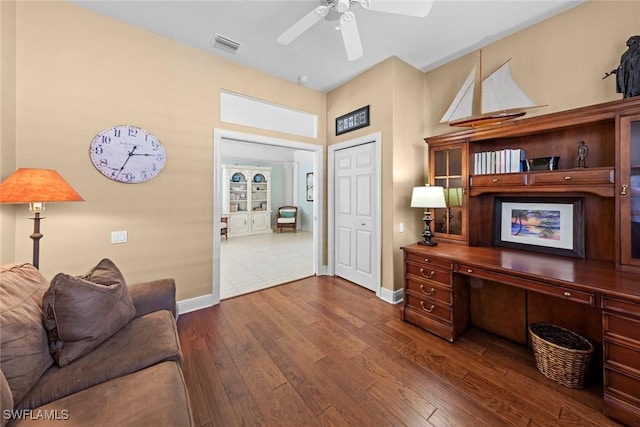 office space with a ceiling fan, visible vents, dark wood finished floors, and baseboards