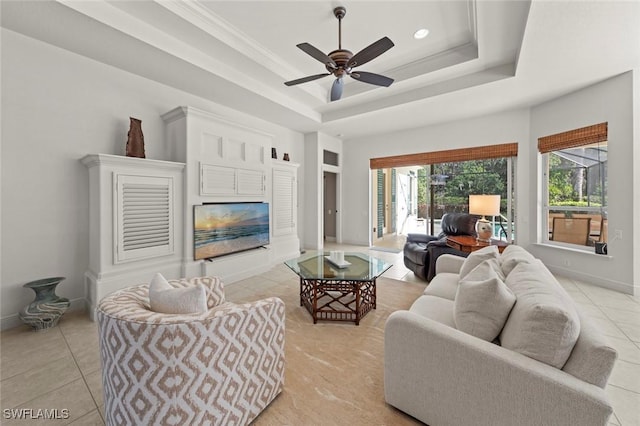 living area featuring light tile patterned floors, baseboards, a raised ceiling, and a glass covered fireplace