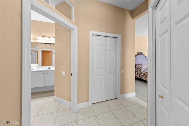 hallway with a sink, baseboards, and light tile patterned floors