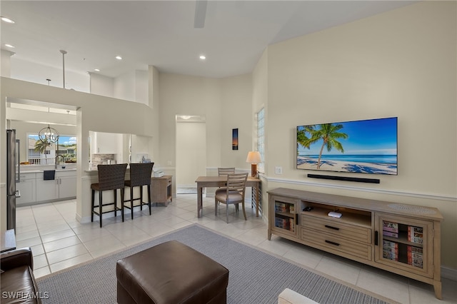 living room with a towering ceiling, recessed lighting, a chandelier, and light tile patterned flooring