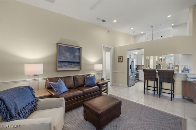 living room featuring light tile patterned floors, recessed lighting, a notable chandelier, a high ceiling, and visible vents