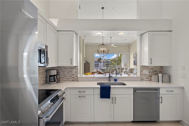 kitchen with stainless steel appliances, white cabinetry, a chandelier, pendant lighting, and a sink