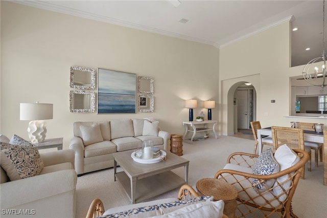 carpeted living room with an inviting chandelier, a high ceiling, arched walkways, and crown molding