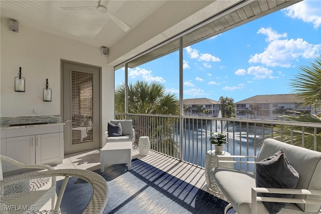 sunroom / solarium with a water view, a residential view, and a ceiling fan