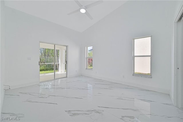 empty room featuring marble finish floor, baseboards, high vaulted ceiling, and a ceiling fan