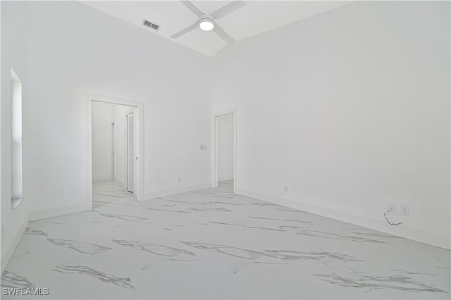 empty room with ceiling fan, marble finish floor, a high ceiling, and visible vents