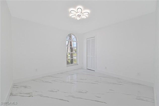 spare room with marble finish floor and baseboards