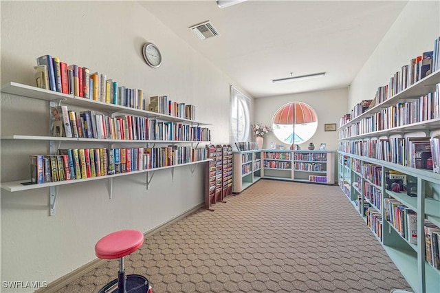interior space with bookshelves, visible vents, and carpet floors