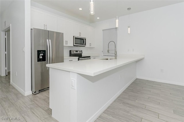 kitchen featuring white cabinets, stainless steel appliances, light countertops, pendant lighting, and a sink