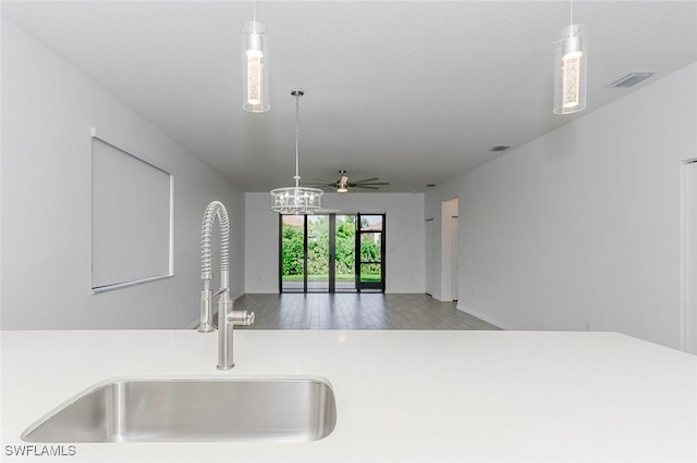 kitchen with decorative light fixtures, light countertops, visible vents, open floor plan, and a sink